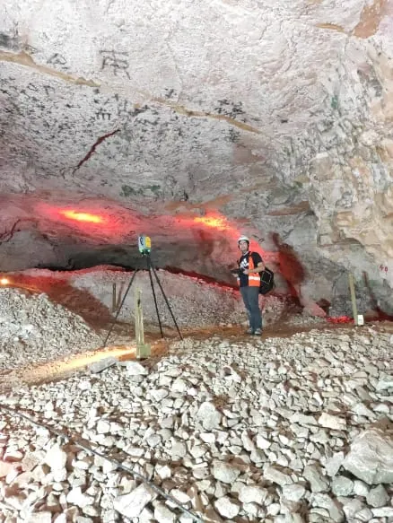 מודד עם קסדה ליד סורק לייזר על רצפת הסלעים באולם המערה
